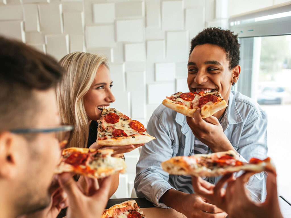 Smiling people eating pizza