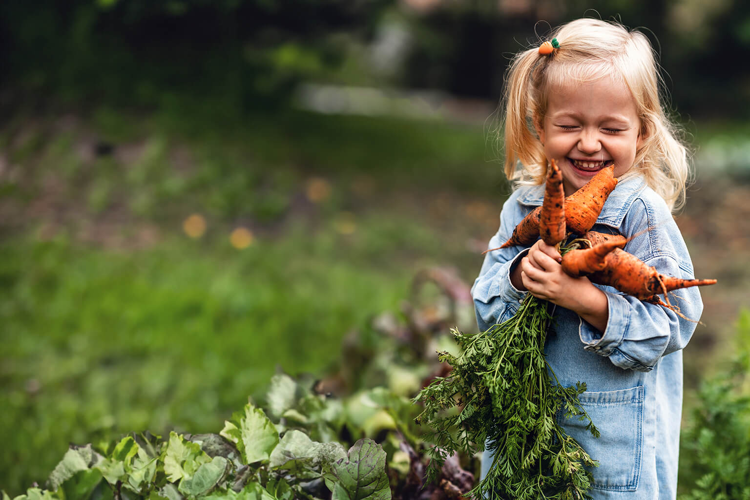 Young girl smiling holding carrots